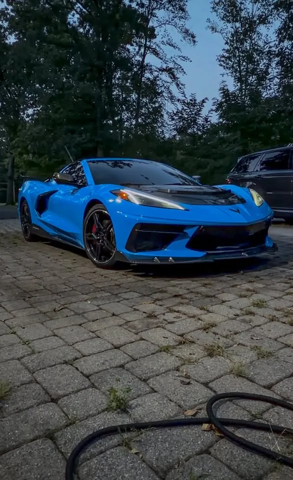 A blue C8 Corvette on a paved driveway after a full detail