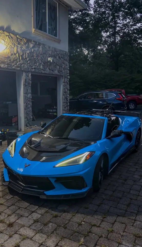 A blue C8 Corvette parked outside a garage at dusk after detailing
