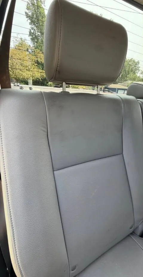 A grey leather rear seat marked with staining, before cleaning