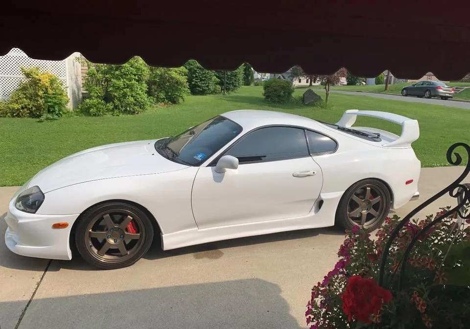 A white Toyota Supra with bronze wheels on a driveway after a detail