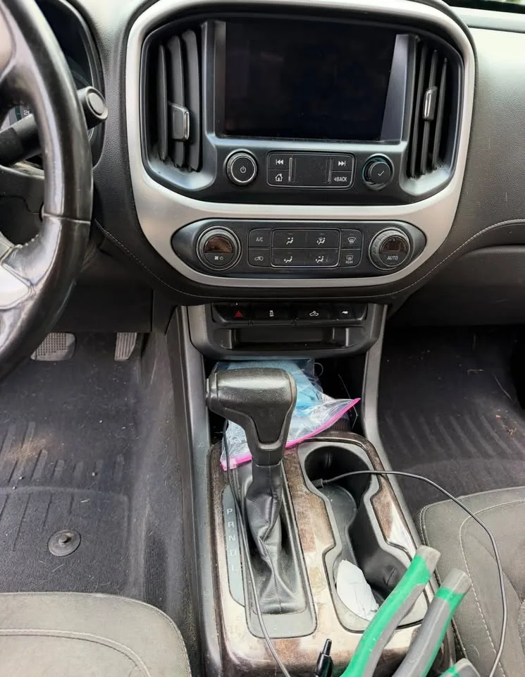 A truck centre console part way through a clean, with a vacuum hose across the seat